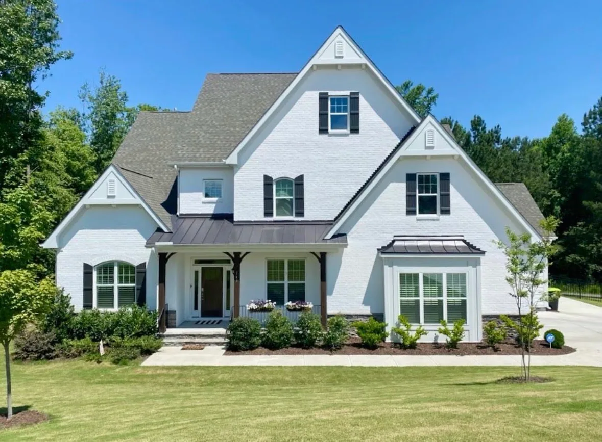 Two-story home with freshly painted white brick, gray roof and black accents