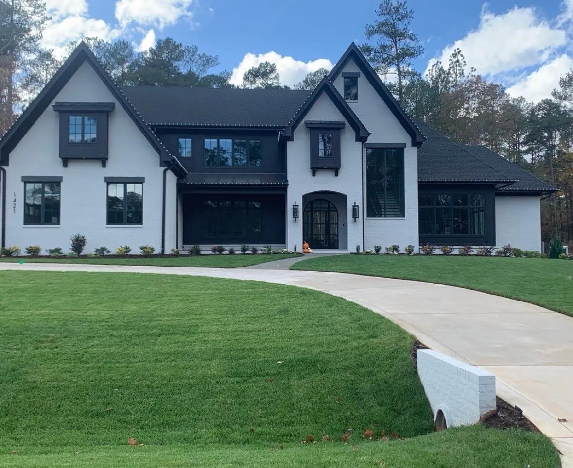 Two-story home with freshly painted white brick and black windows and trim