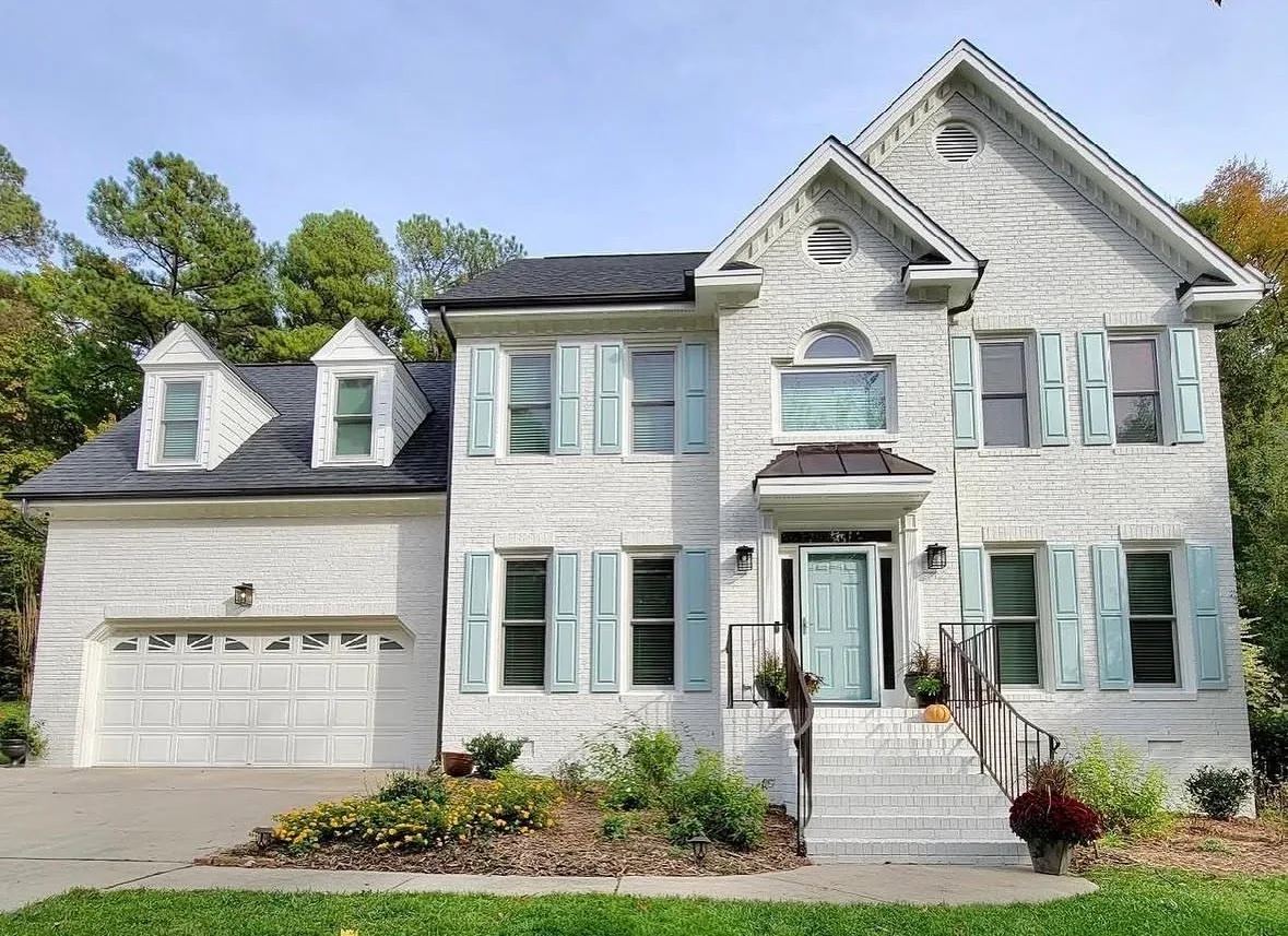 Two-story home with freshly painted white siding and light green shutters