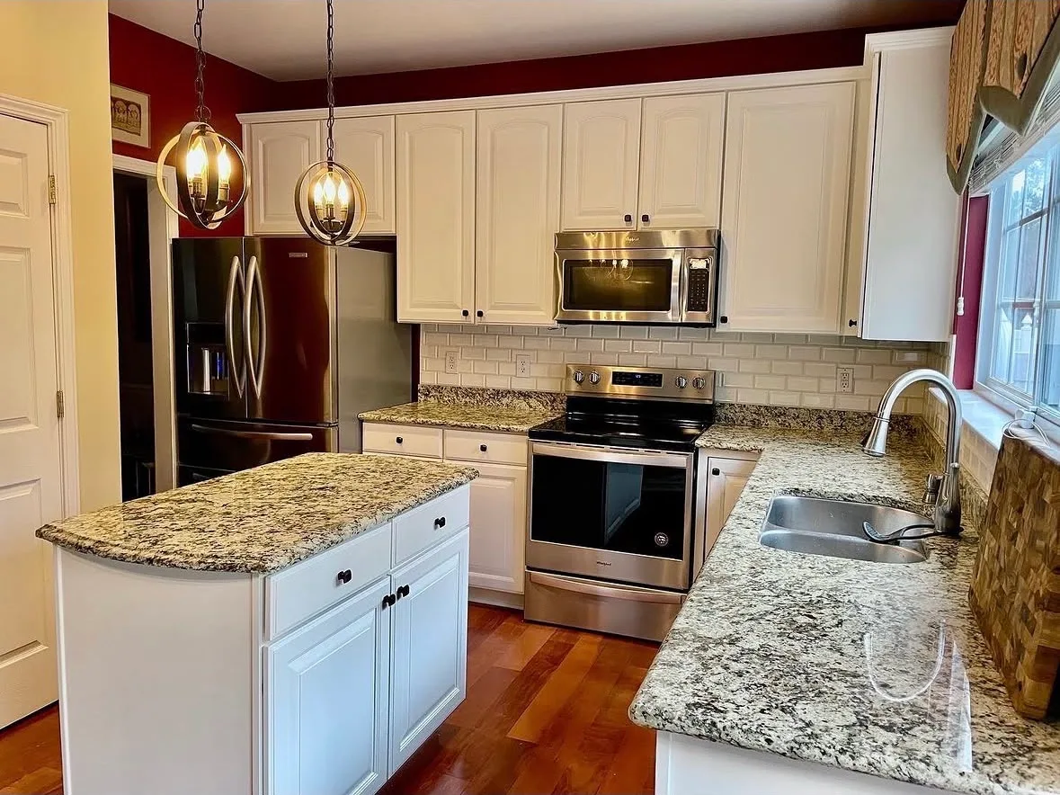 Kitchen with freshly painted white cabinets, granite countertops and pendant lights