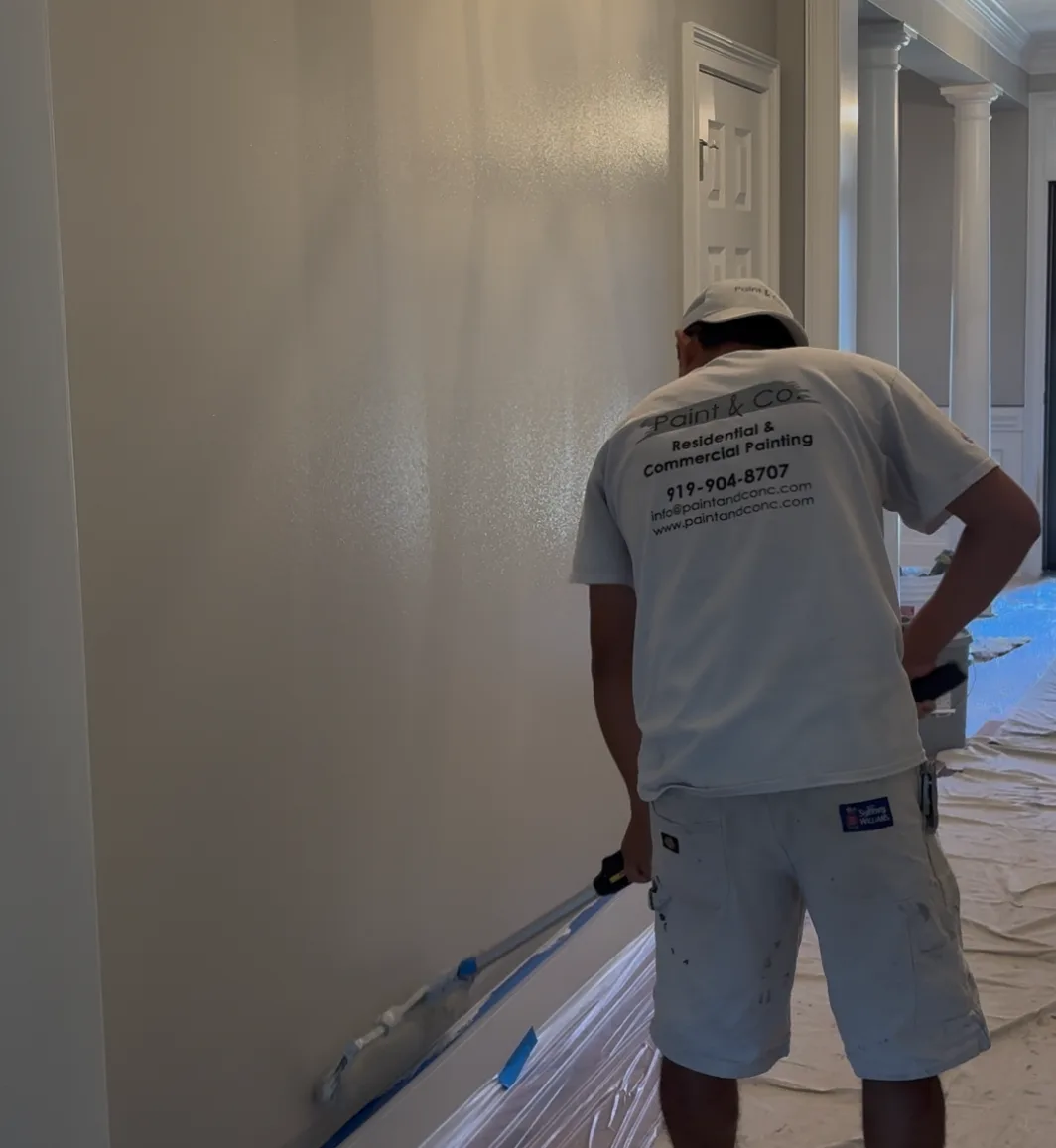 Painter working along an interior wall with the floor covered and taped
